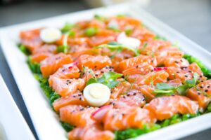 Delicious salmon sashimi garnished with quail eggs and fresh greens on a platter.