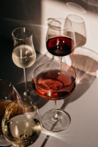 A sophisticated display of different wine glasses with red, white, and rose wine in natural light.